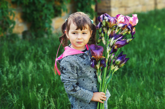 Little girl holding a bouquet of irises . Baby with flowers