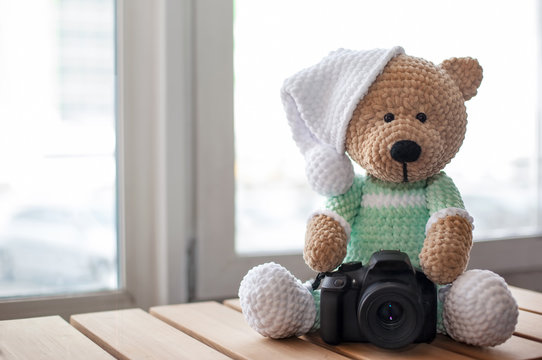 Teddy bear with camera on wood table. Copy space. Selective focus