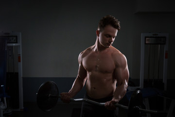 Close up of young muscular man lifting weights over dark background