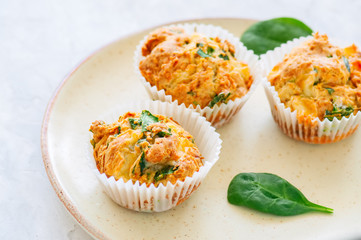 Savory potato spinach and feta muffins served on a plate. White stone background.