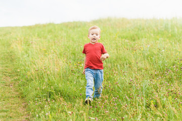 Little boy running across the field on the lawn on a summer day