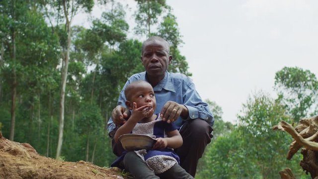 Man standing by his daughter while she is eating