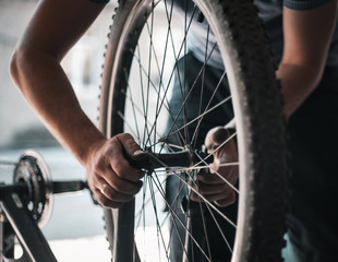 A guy athlete serves and repairs his mountain bike in the garage