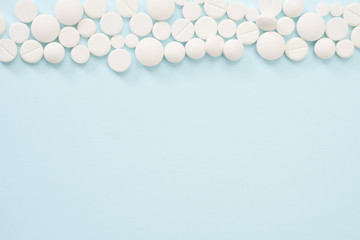 Heap of white pills on blue background