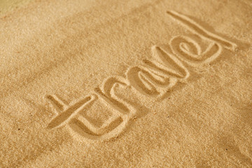 written words travel on sand of beach with wave background