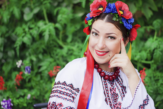 Portrait Happy Ukrainian woman with a poppy wreath in national clothes