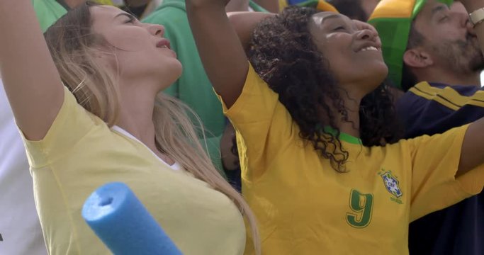 Brazilian football fans dancing and cheering at match, slow motion