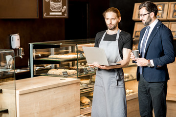 Businessman and barista working in the pastry shop