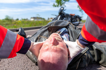 A german paramedic removes an helmet from an injured biker. Rettungsdienst is the german word for...