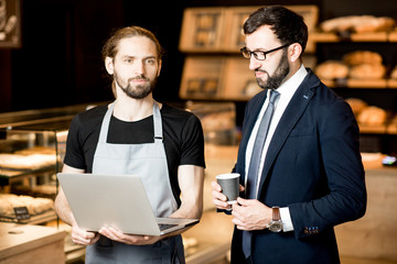 Businessman and barista working in the pastry shop