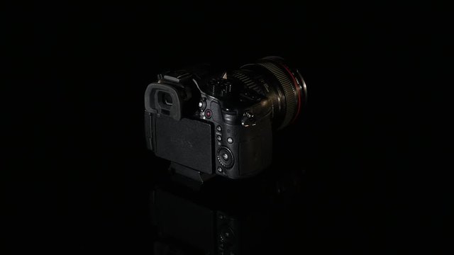 Professional digital photo camera rotate on black background
