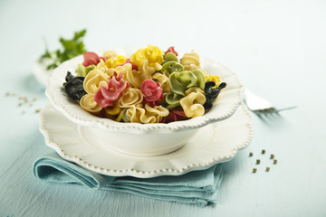 Colorful dried pasta in white bowl