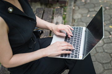 business woman sit on the chair at public place and typing word into laptop