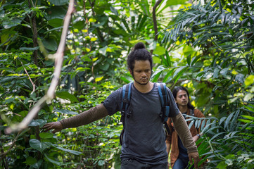 travelers walking through jungle. two man hiking in forest dense. concept of Travel relax, Holiday and vacation.