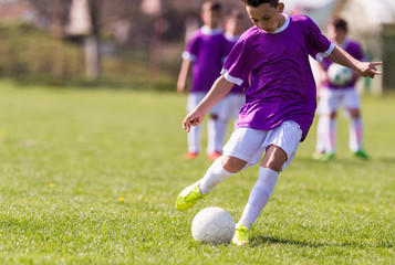Boy kicking football on the sports field