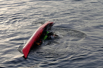 Man in red kayak doing eskimo roll on river