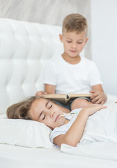 Fototapeta premium Little boy reads the book to his sick sister