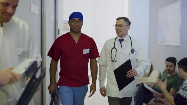 Doctors talking while walking along hospital corridor