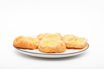 A plate of  of mini danish pastries with lemon cheesecake filling on top, white background.