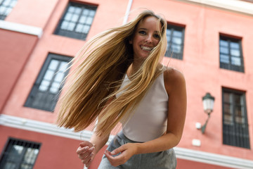 Happy young woman with moving hair in urban background.