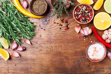 Green rosemary and mixed spices on wooden kitchen table top view. Ingredients for cooking. Food background.