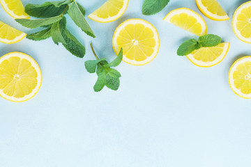 Juicy lemon slices and mint leaves on blue table top view. Flat lay style.