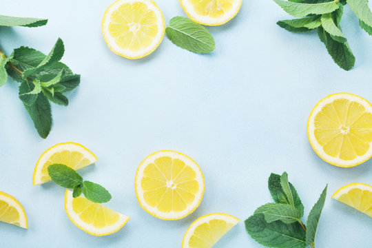 Lemon slices and mint leaves on blue pastel table top view. Ingredients for summer lemonade and cocktail. Flat lay style.