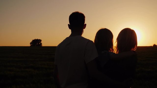 Young family with a child looking at a beautiful sunset