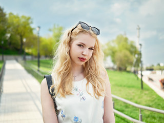 Close up of blonde student girl posing in park, enjoying warm sun light, recreation and relaxation on spring holiday