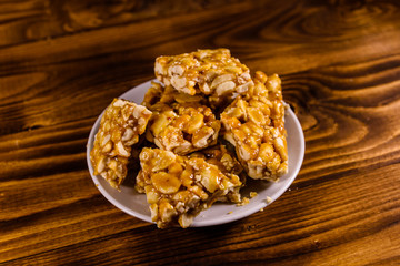 Ceramic plate with peanut brittles on wooden table.