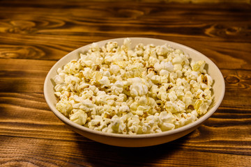 Ceramic plate with popcorn on wooden table