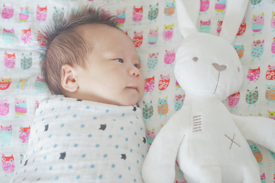 Cute Adorable Newborn Baby Boy Wrapped Or Swaddle In A Blanket, Sleeping And Sometime Both Eyes Open In Kids Bed