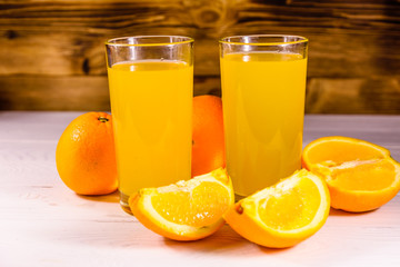 Oranges and glasses with orange juice on a wooden table