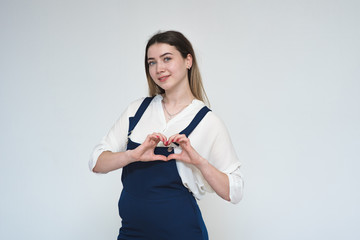 Fototapeta premium Portrait of a beautiful girl on a white background showing a heart with her hands