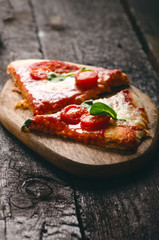 Italian food, cuisine. Margherita pizza on a black, wooden table with igredients like tomatoes, salad, cheese, mozzarella, basil. Delicious homemade food. 