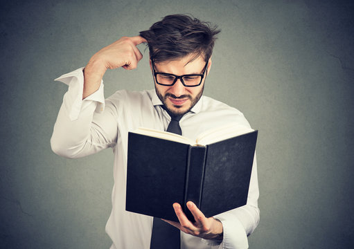 Puzzled man with book on gray
