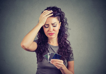 Sad stressed woman looking at too many credit cards