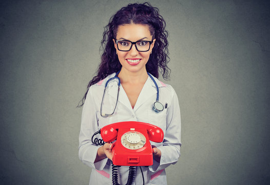 Smiling female doctor holding a telephone ready to answer phone calls