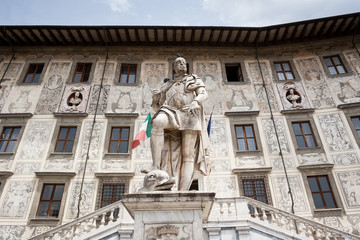 Obraz premium A statue of Cosimo I subduing a dolphin in front of Palazzo della Carovana in Pisa Knights Square, made by artist Pietro Francavilla in 1596 in Pisa, Italy.