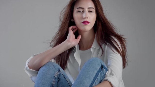 woman in industrial studio wears jeans and white shirt blowing long hair rose bright lips. Classick jeans outfit Closeup portrait