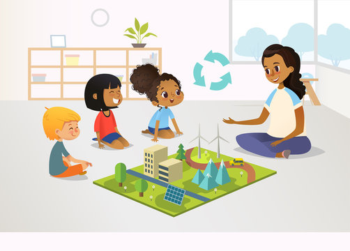 Smiling female kindergarten teacher and children sit on floor and explore toy model with renewable or sustainable energy systems, wind and solar eco friendly power stations. Vector illustration.