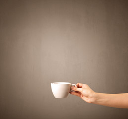 Young female hand holding coffee cup with brown background