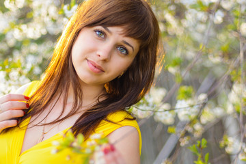 young cute girl in yellow dress in spring on cherry blossom background