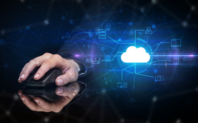 Hand using wireless mouse in a dark environment with cloud technology and online storage concept