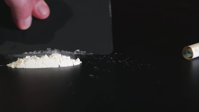 Narcotic concept. Hand of man doing line of cocaine powder near rolled banknote