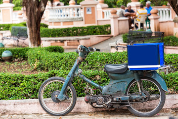 Fototapeta premium Motorcycle with a blue trunk on a city street, Santo Domingo, Dominican Republic. Close-up.