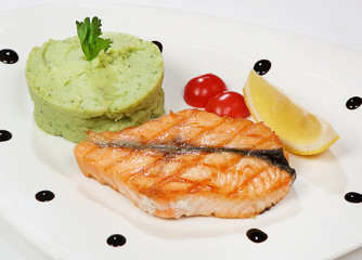 Salmon steak served with mashed potatoes, broccoli and cherry tomatoes