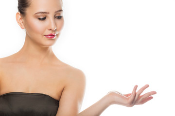 Naklejka premium Beauty spa woman with perfect skin portrait. Beautiful brunette spa girl showing empty copy space on the open hand palm for text. Proposing a product.