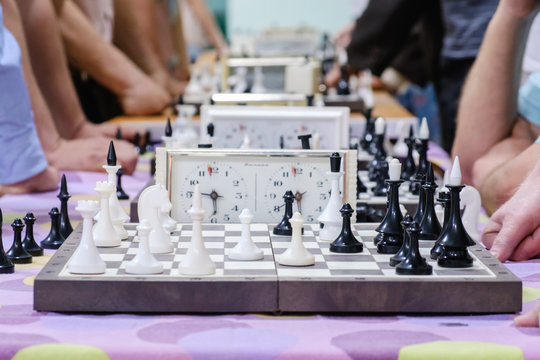 Chess board with pieces and clock on wooden desk In connection with the chess tournament.