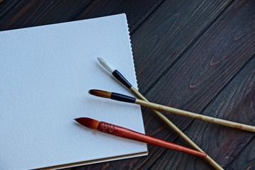 three tassels on a white sheet of notepad on a wooden table